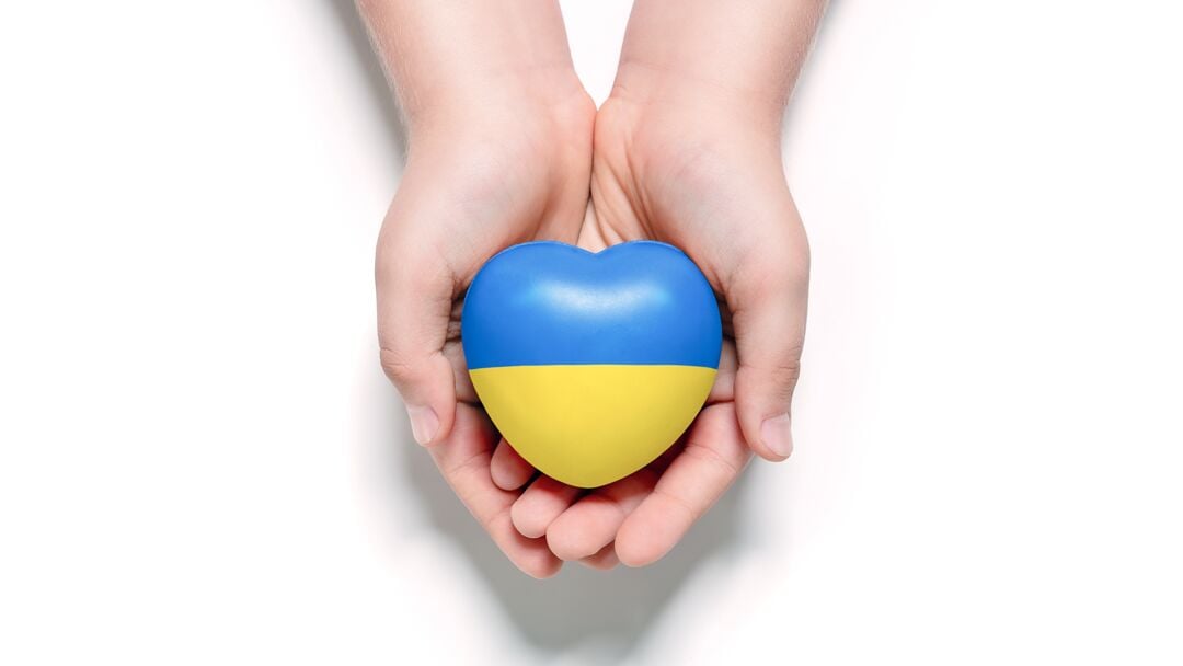 Web_Desktop-High angle view of child hands holding ukraine flag painted heart isolated on white background